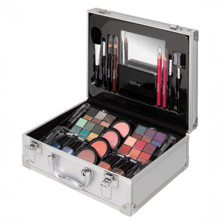 An open silver makeup case filled with cosmetics, including eyeshadow palettes, blushes, lip colours, brushes, and an internal mirror, shown on a white background.