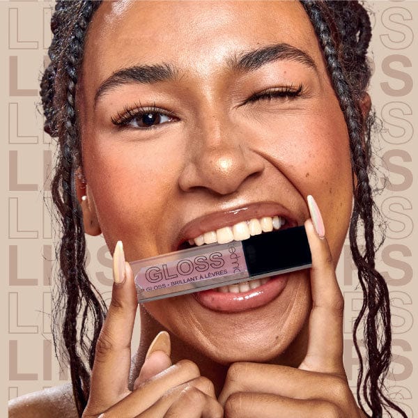 Model holding one of the lip glosses and biting it.