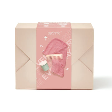 The hair care gift set on a white background. The giftset is in a beige box with a pink seal to show the contents inside. It includes a pink hair towel, a beige comb and hair mask.